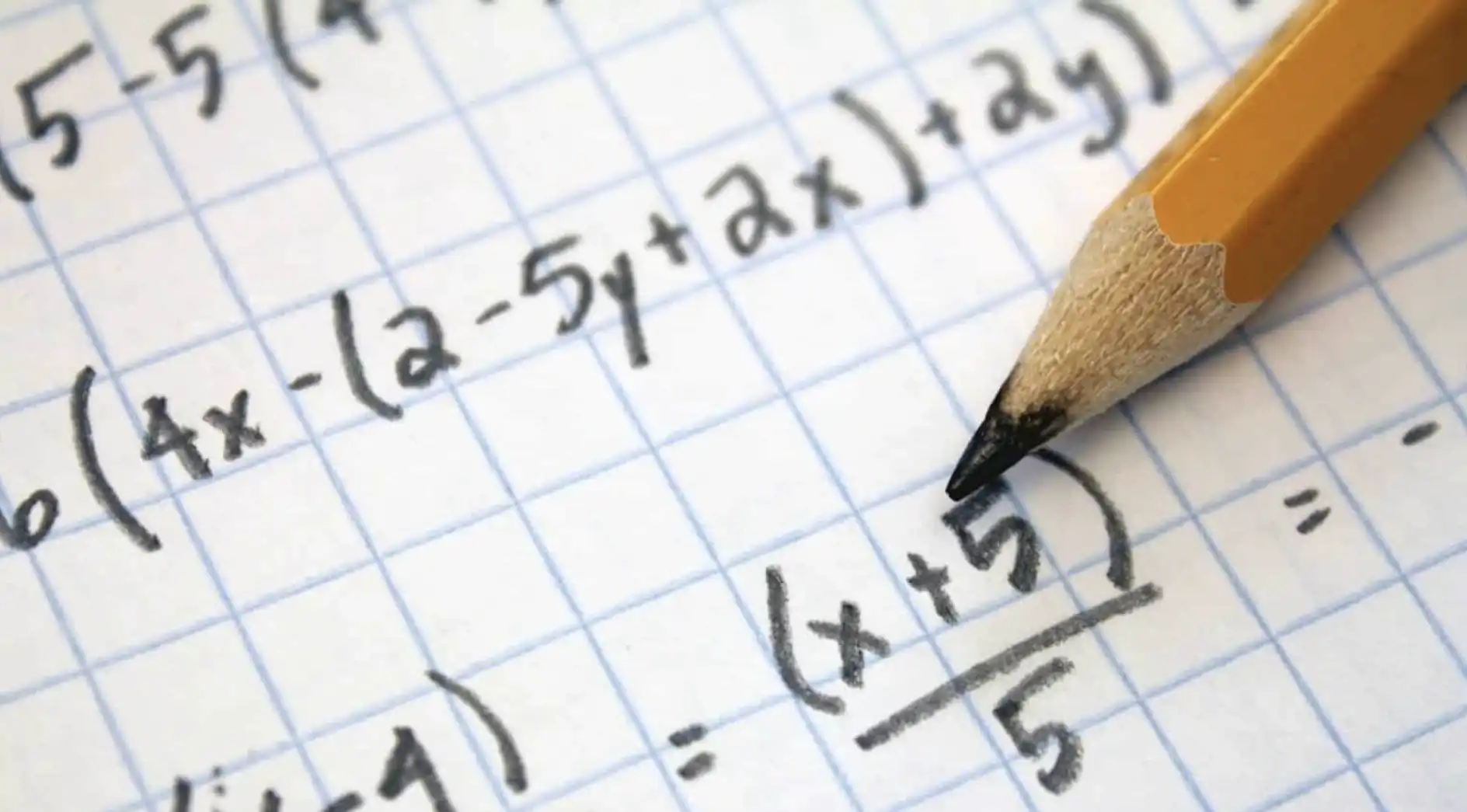 Uma pessoa está fazendo anotações de matemática em uma folha de papel quadriculado, usando um lápis.