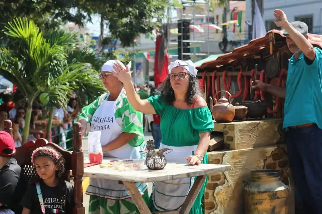 Mulheres vestidas com roupas típicas italianas em um festival ao ar livre.