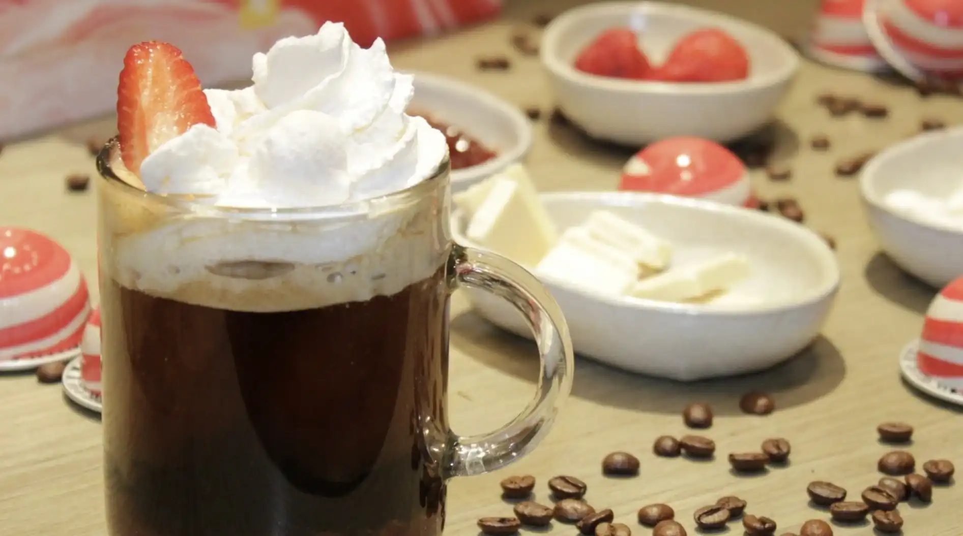 Uma bebida de café gelada coberta com chantilly e um morango.