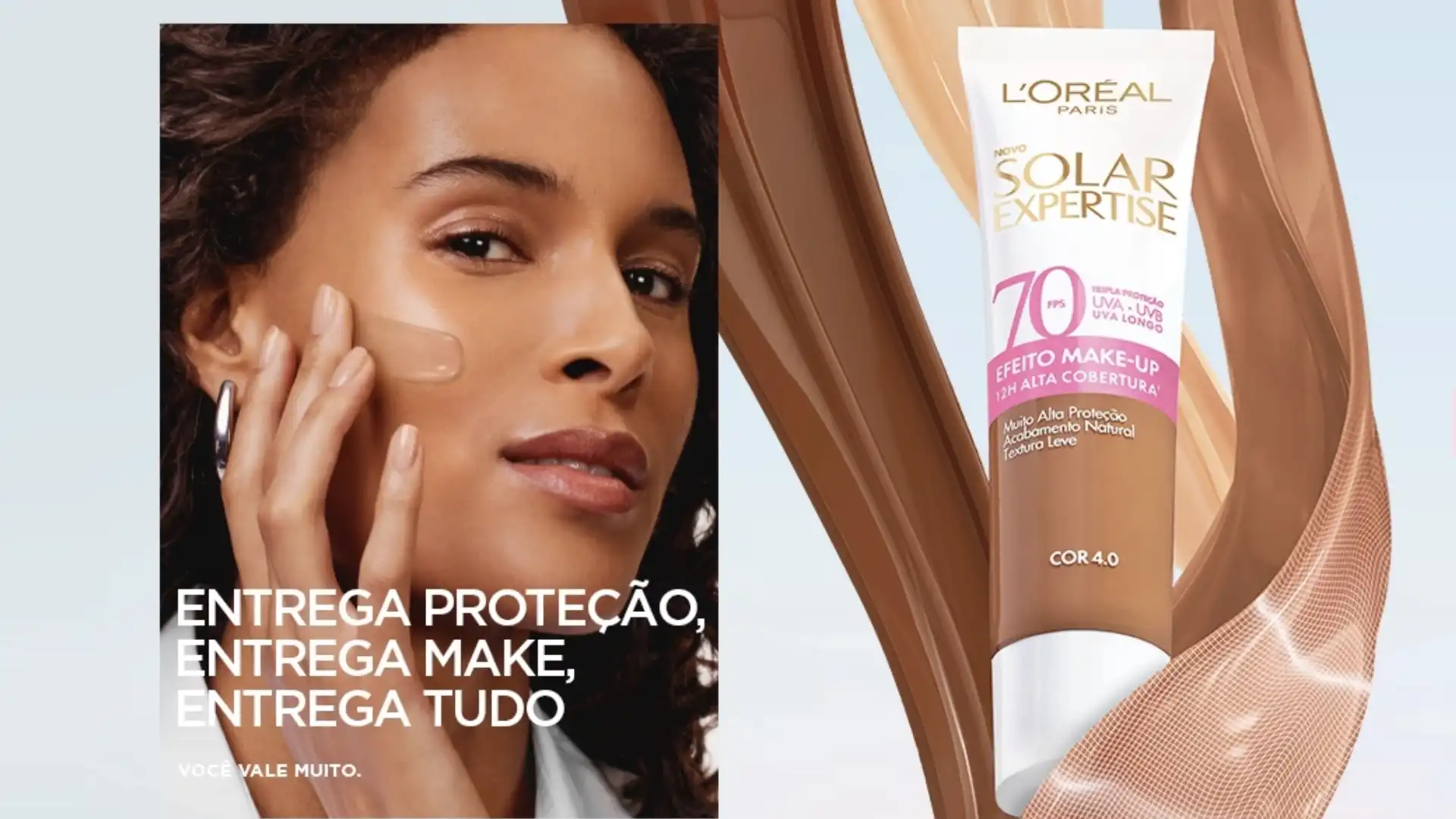 Mulher com pele morena aplicando protetor solar com cor L'Oréal Paris Solar Expertise no rosto, ao lado de um tubo do produto.