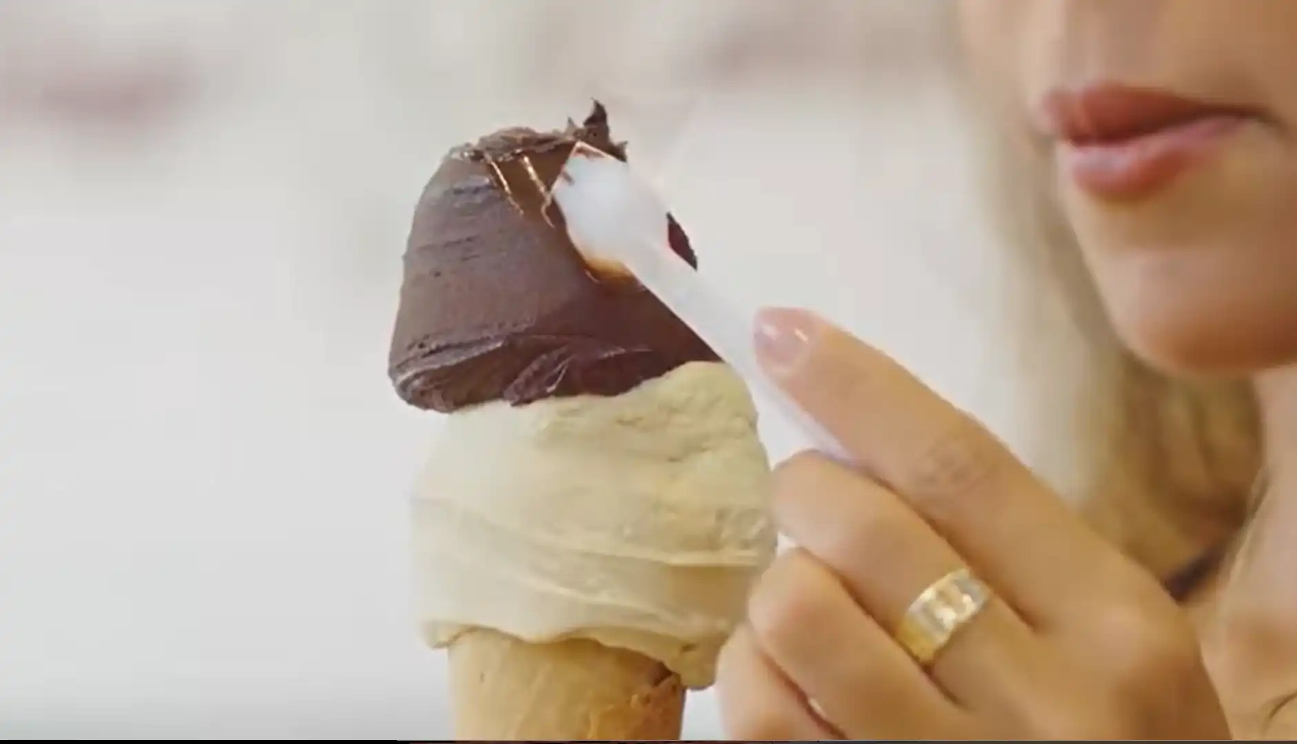 Uma pessoa segura uma casquinha com duas bolas de gelato de chocolate.