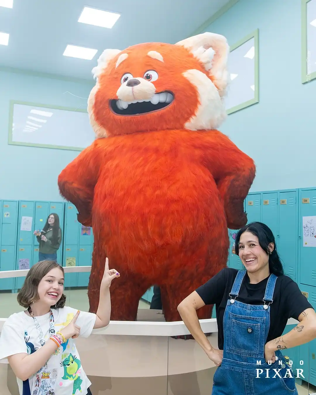 Duas mulheres em frente a uma grande estátua do panda vermelho, personagem do filme 'Red: Crescer é uma Fera'.
