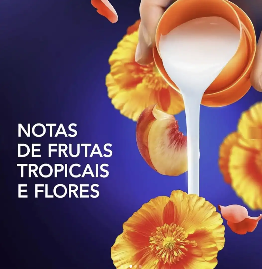 Uma tampa laranja de Downy derramando um líquido branco e cremoso contra um fundo azul escuro.