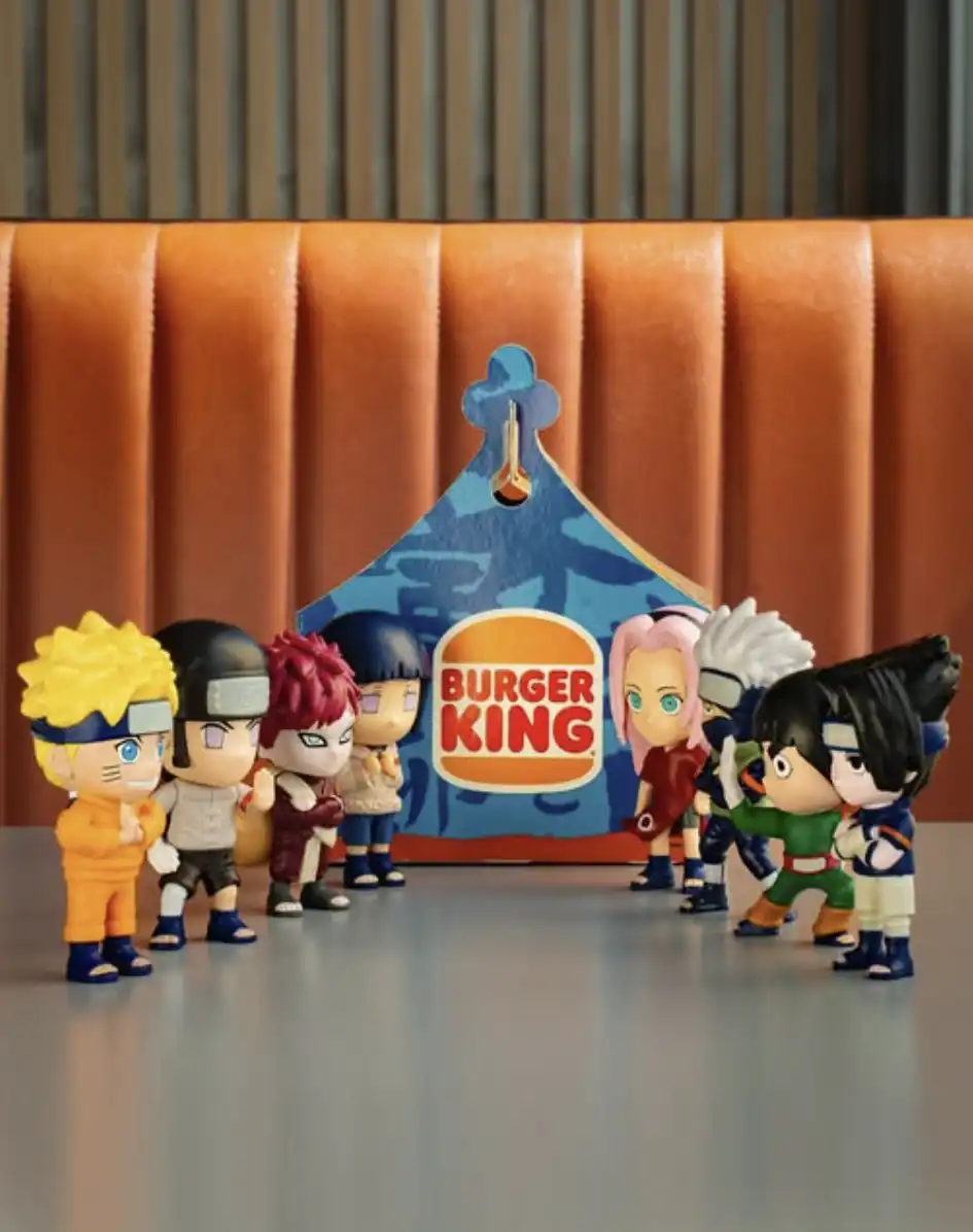 Foto de nove bonecos colecionáveis de personagens de Naruto, dispostos em duas fileiras de frente para uma caixa de papelão triangular do Burger King com estampa azul.