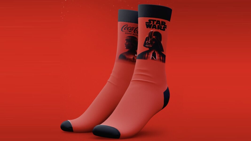 Meias colecionáveis vermelhas da Coca-Cola Zero Açúcar e Star Wars, com a silhueta de Luke Skywalker em uma e Darth Vader na outra, em um fundo vermelho.