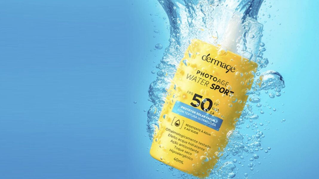 Frasco amarelo de protetor solar Dermage Photoage Water Sport FPS 50 em meio a respingos d'água.