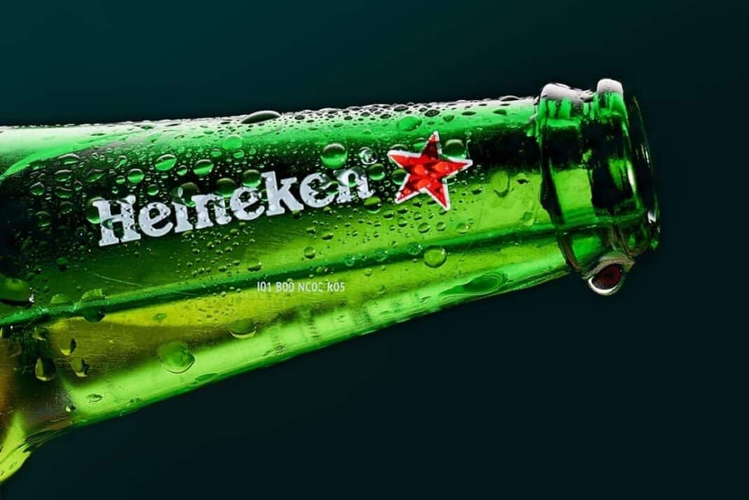 Garrafa de cerveja Heineken verde e molhada, em fundo escuro.