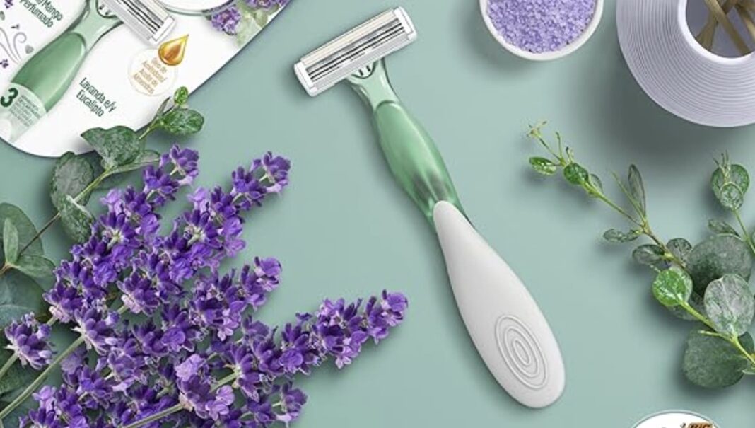 Aparelho de depilar feminino verde e branco ao lado de um buquê de lavanda.
