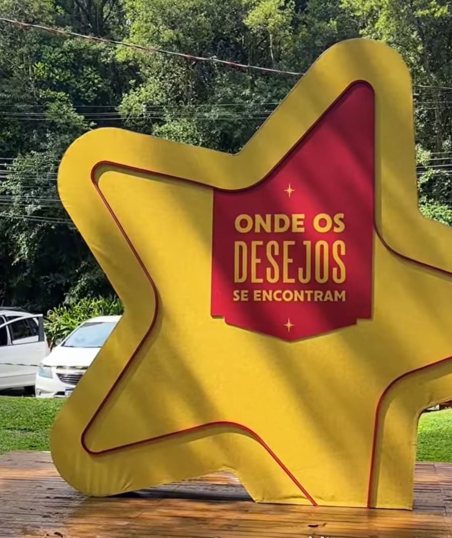 Grande estrela amarela e vermelha com a frase "ONDE OS DESEJOS SE ENCONTRAM" em um parque.
