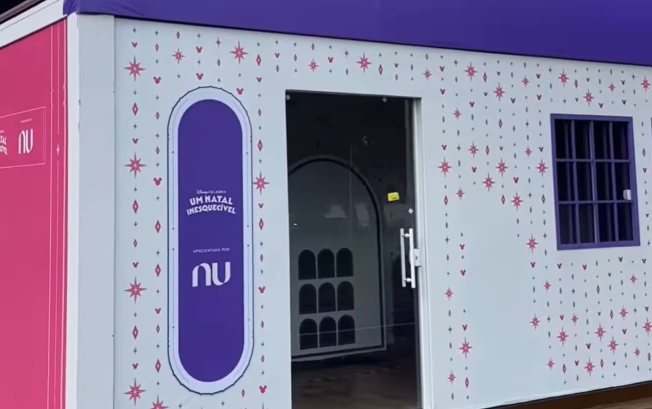 Estrutura branca decorada com estrelas e logotipos da Disney e Nu (Nubank) com a frase "Um Natal Inesquecível".