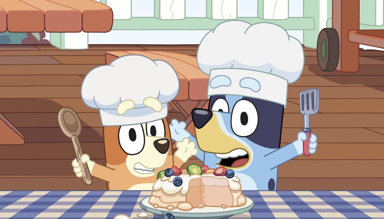 Mascotes de Bluey e Bingo em fantasias de chef em uma atração temática de cozinha de massinha para crianças.
