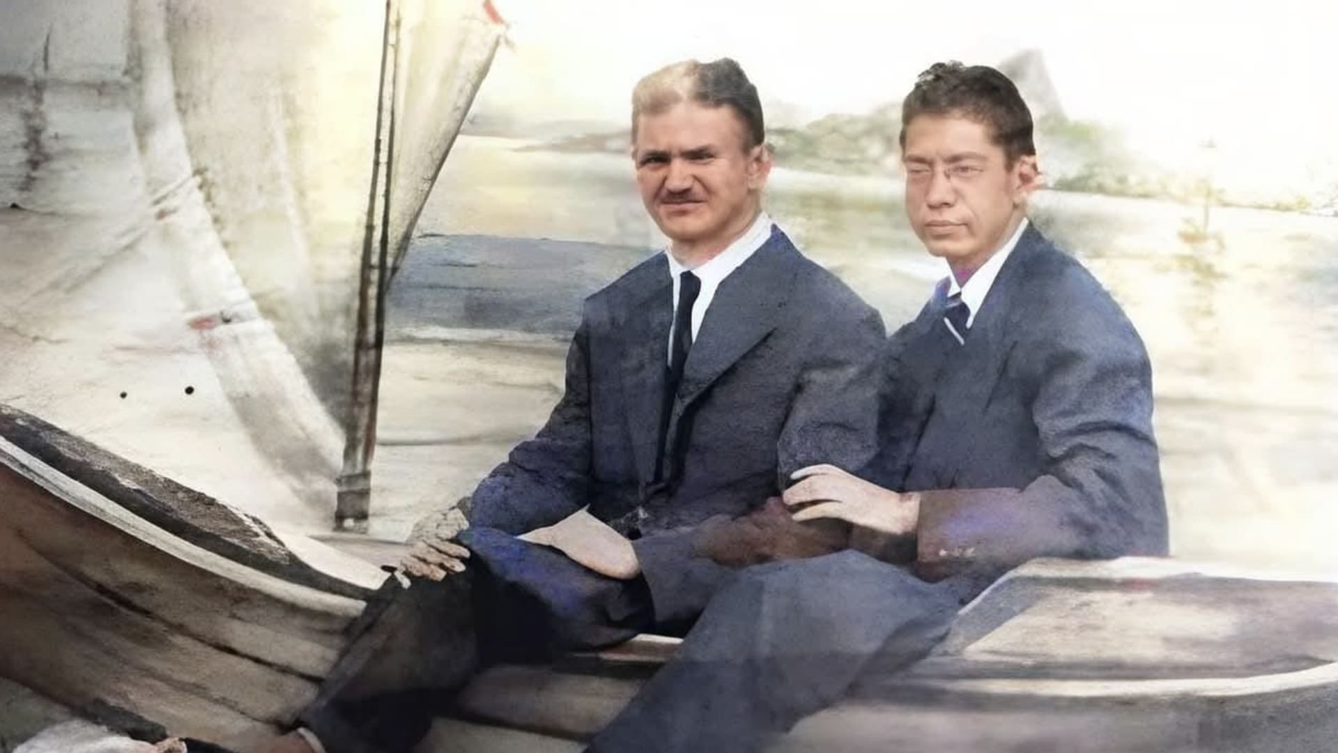 Fotografia antiga colorizada de Poty Lazzarotto e Dalton Trevisan sentados lado a lado em um barco de madeira. Ambos vestem ternos escuros, camisas brancas e gravatas. O cenário ao fundo sugere uma paisagem litorânea no Rio de Janeiro, com tons suaves e envelhecidos.