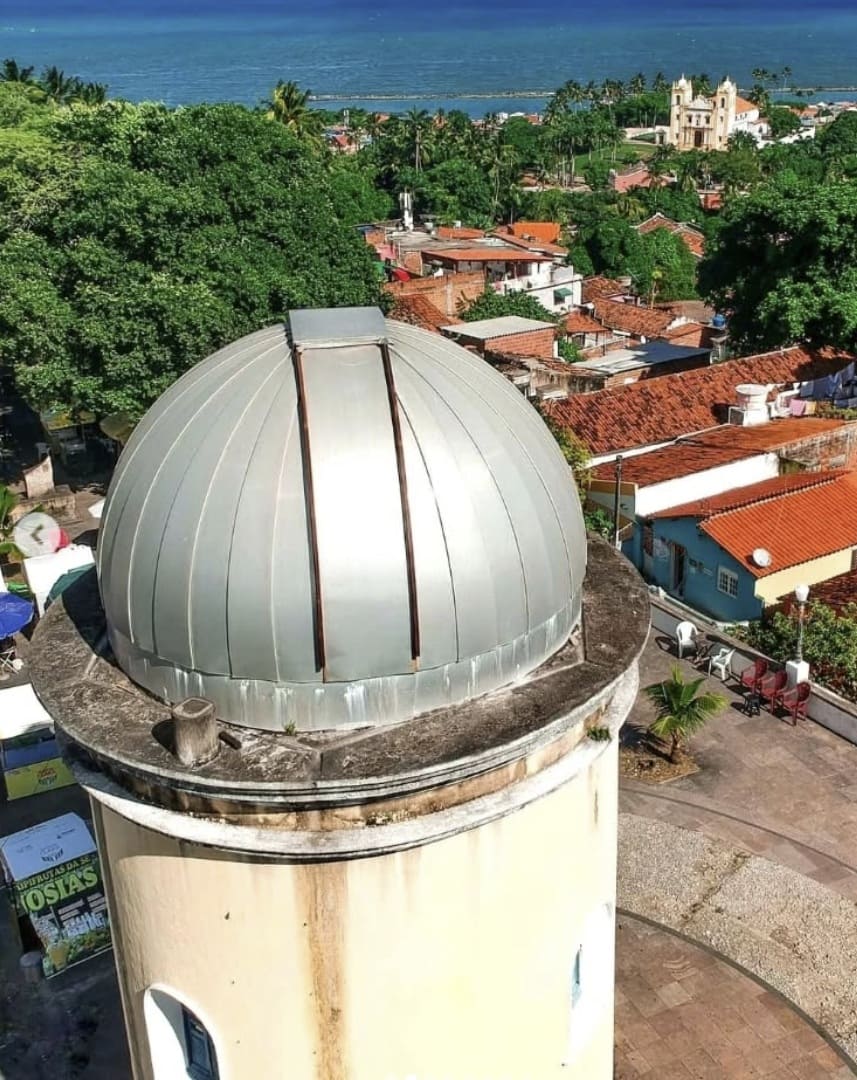 Fotografia com tom dourado do Observatório de Olinda em primeiro plano e a Igreja da Sé ao fundo, entre árvores.