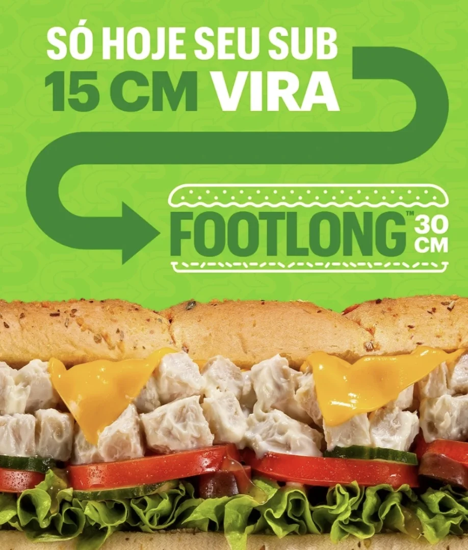 Banner promocional da Subway com fundo verde, anunciando que apenas hoje o sanduíche de 15 cm vira um Footlong de 30 cm. Abaixo, detalhe de um sanduíche recheado com frango, queijo derretido, alface e tomate.