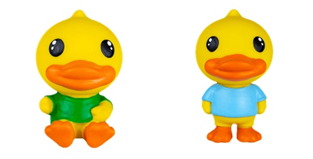Dois bonecos de vinil do personagem B.Duck lado a lado sobre fundo branco. O da esquerda está sentado e veste uma camiseta verde; o da direita está de pé e veste uma camiseta azul.