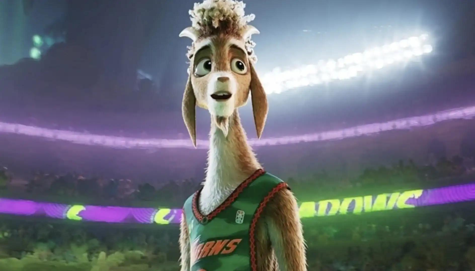 Close-up de uma cabra antropomórfica, protagonista do filme "Um Cabra Bom de Bola", em uma arena esportiva iluminada. Ela tem pelos marrons, um topete de lã clara e veste uma regata de basquete verde com detalhes em vermelho. Sua expressão é de admiração ou surpresa.