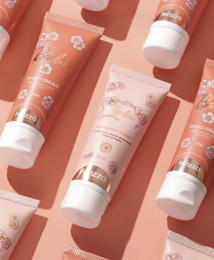 Pote redondo do Esfoliante Corporal Fenzza Barbie em tom rosa pastel, decorado com ilustrações de flores e laços sobre um tecido de cetim.