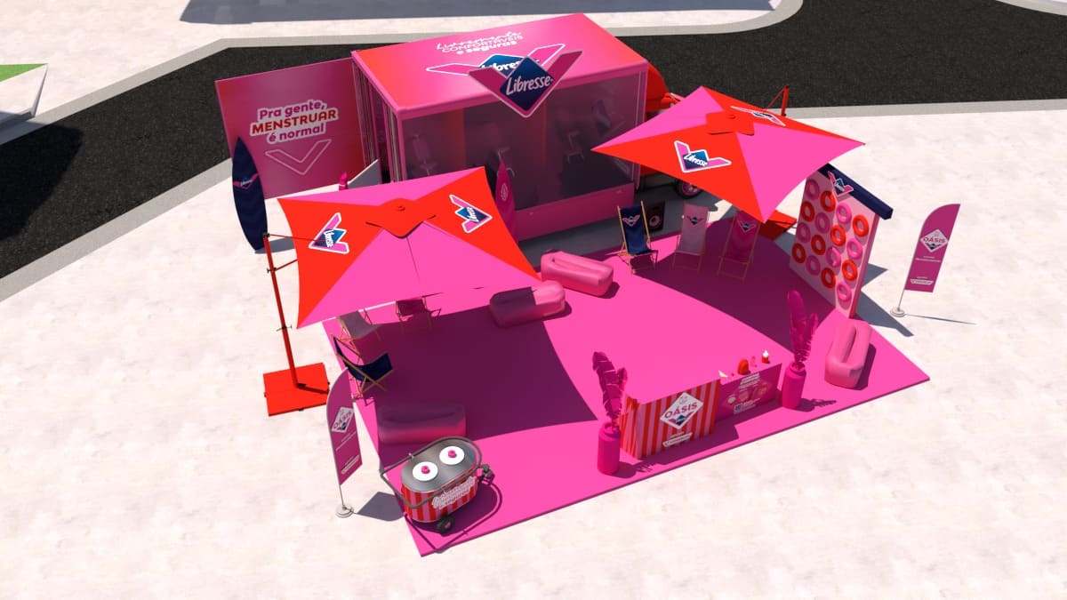 Renderização 3D de um estande de ativação da marca Libresse em tons vibrantes de rosa e vermelho. O espaço ao ar livre inclui guarda-sóis, pufes, cadeiras de praia, um balcão de atendimento e painéis informativos com a frase "Pra gente, menstruar é normal".