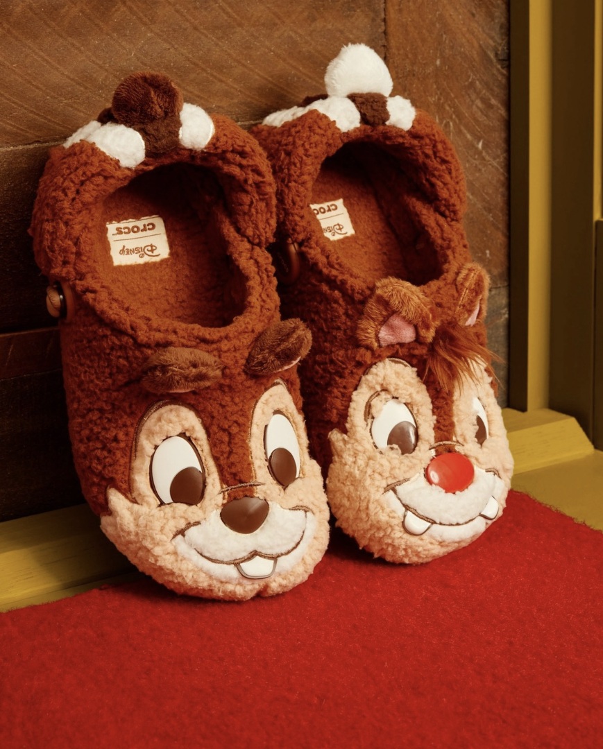 Par de pantufas Crocs marrons e peludas com os rostos dos esquilos Tico e Teco.