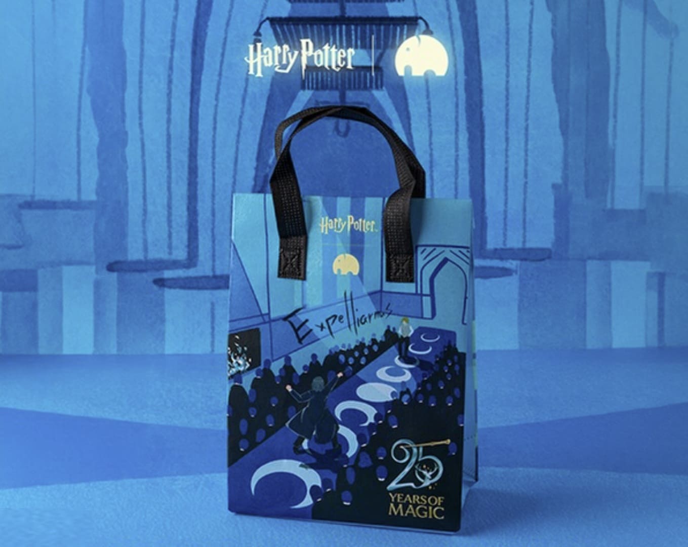 Sacola temática da We Coffee em tons de azul, ilustrando a cena do Clube de Duelo de Harry Potter. A arte mostra Harry lançando o feitiço "Expelliarmus" em uma passarela cercada por alunos, com os logotipos de Harry Potter, We Coffee e o selo de 25 anos.