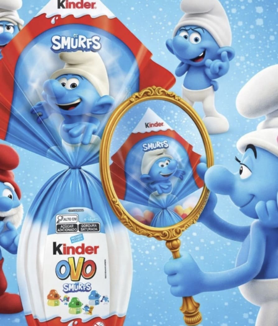 Banner publicitário da Kinder mostrando Smurfette admirando o Ovo de Páscoa dos Smurfs através de um espelho de mão dourado, com o Papai Smurf e outros Smurfs ao fundo.