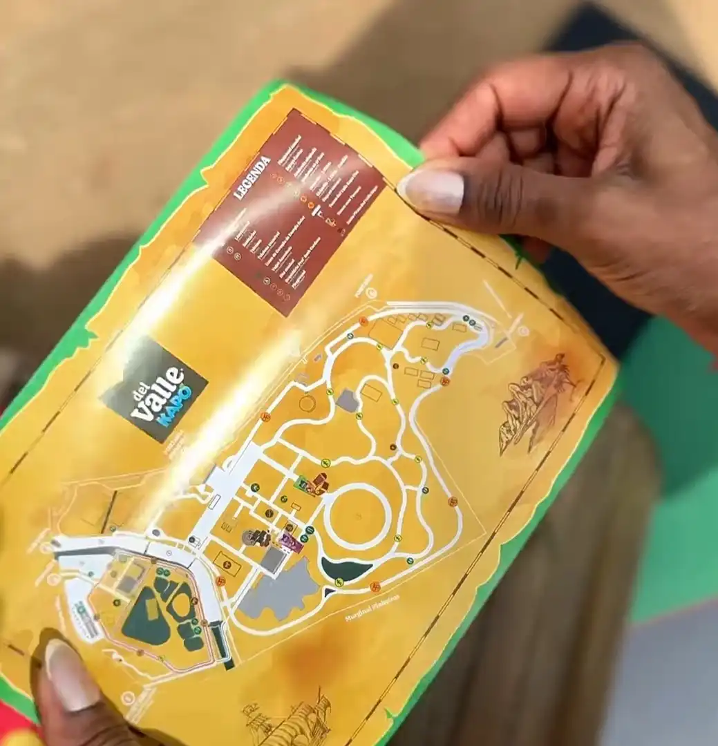 Mãos seguram um mapa impresso colorido do Parque Villa-Lobos, personalizado com a marca Del Valle Kapo, indicando pontos para uma caça ao tesouro.