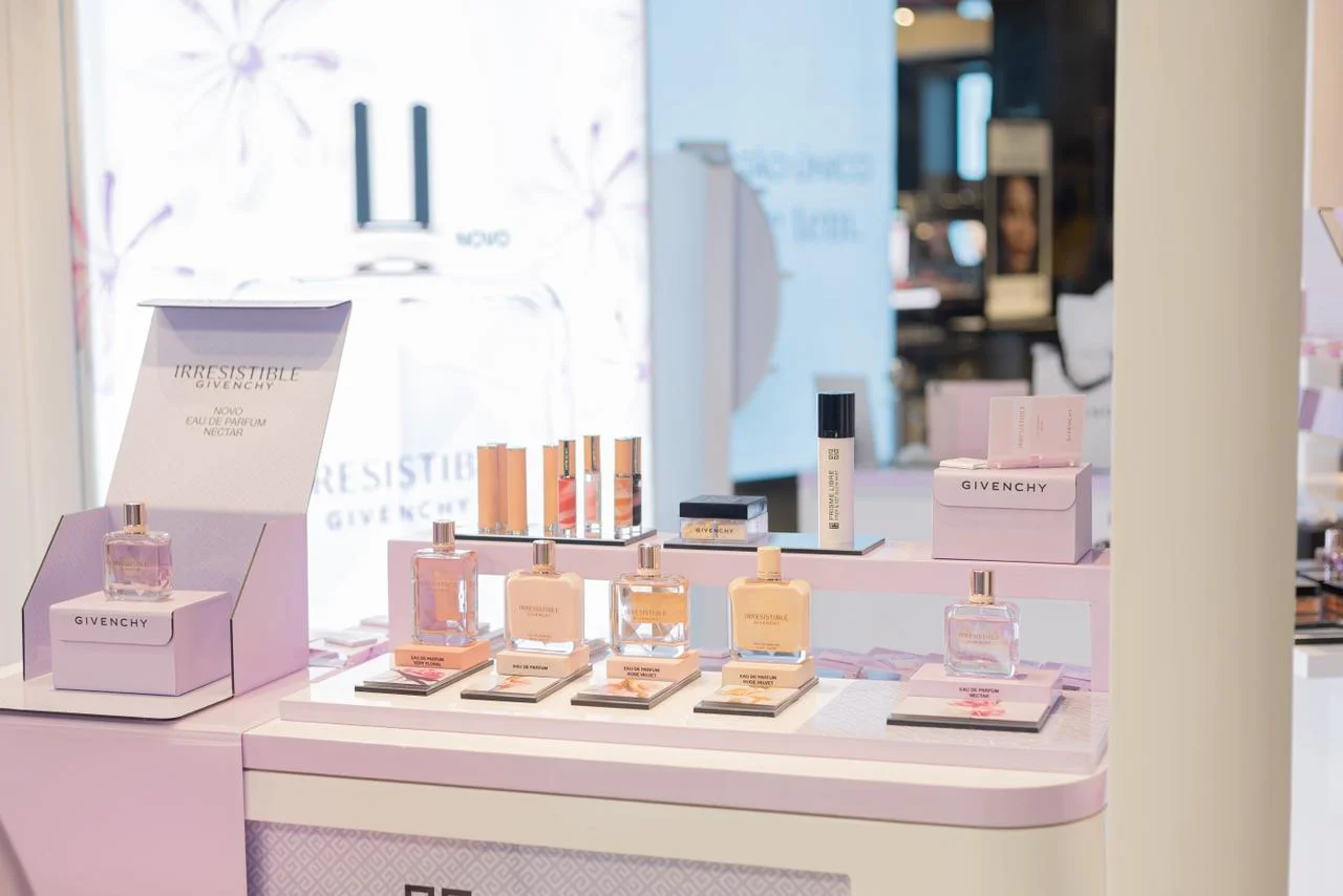 Close em uma exposição de perfumes e maquiagens da Givenchy em uma loja, focando na linha "Irresistible" e "Novo Eau de Parfum Nectar".