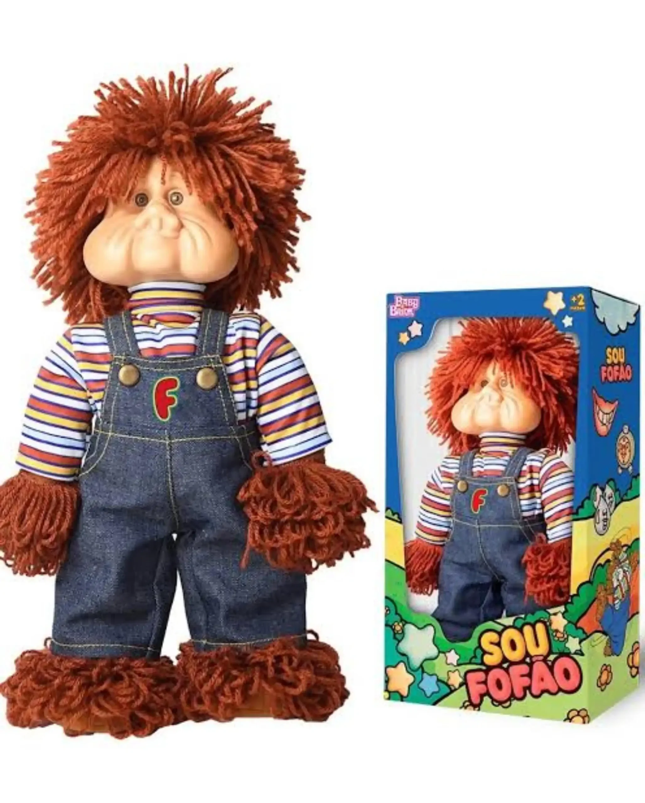Boneco do personagem Fofão, com cabelos de lã ruiva, bochechas grandes e macacão jeans, posicionado ao lado de sua embalagem colorida com os dizeres "Sou Fofão".