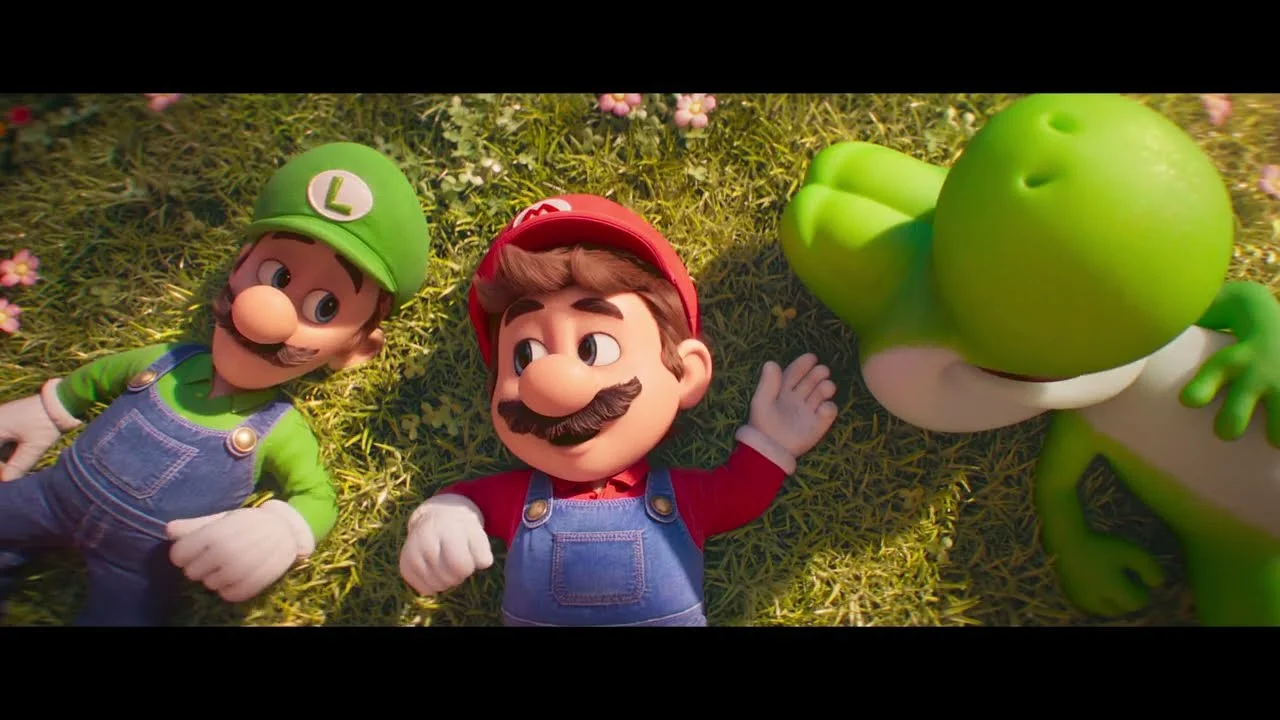 Uma visão de cima para baixo de Luigi, Mario e Yoshi deitados na grama.