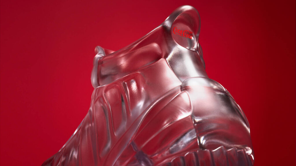 Uma foto de close-up da sola de um tênis de vidro, com o logotipo da Coca-Cola claramente visível e gravado na parte inferior.