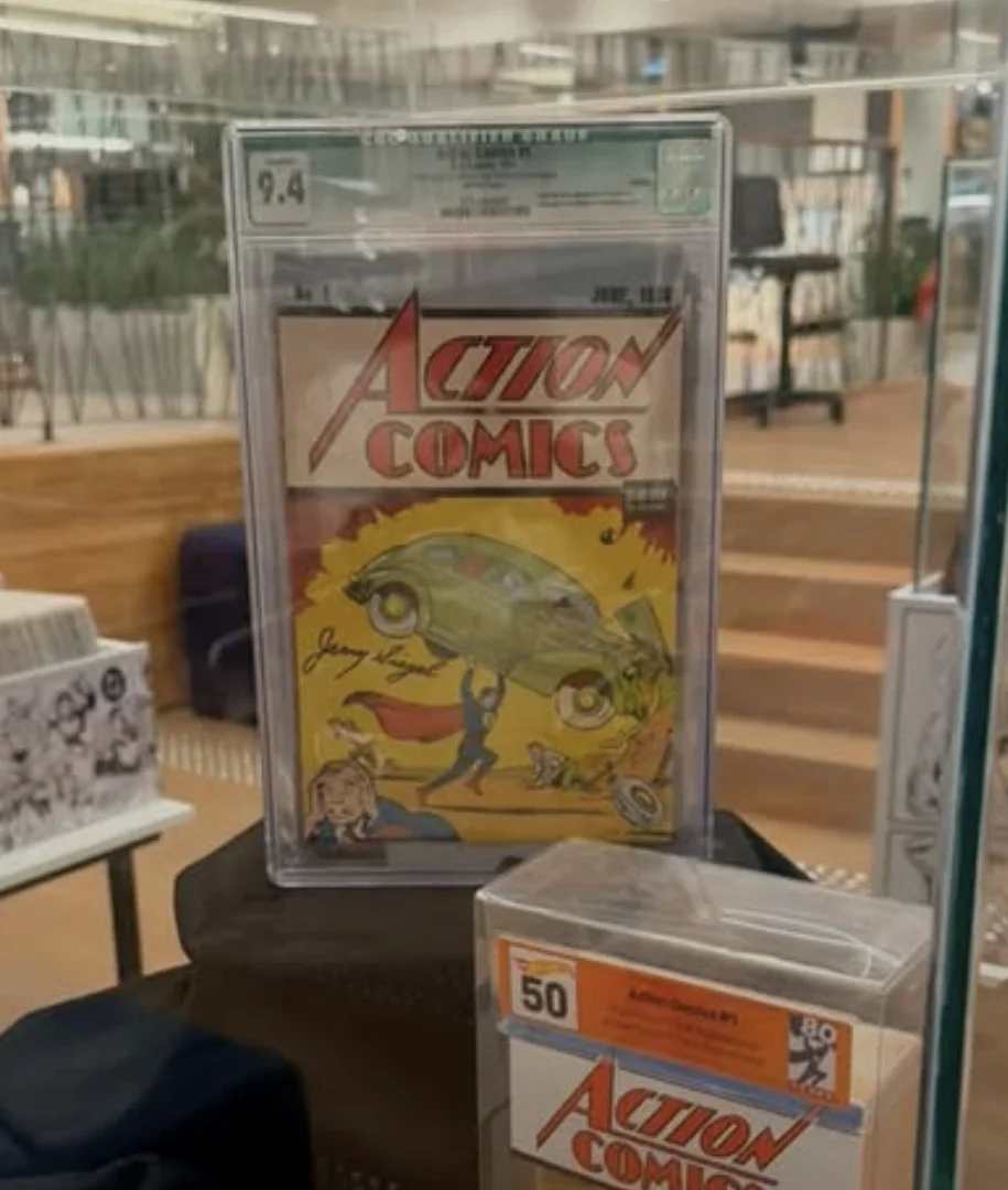 Exemplar da revista em quadrinhos Action Comics número 1, a primeira aparição do Superman, protegida em um estojo de acrílico com selo de graduação 9.4. A capa mostra o herói erguendo um carro verde sobre a cabeça.