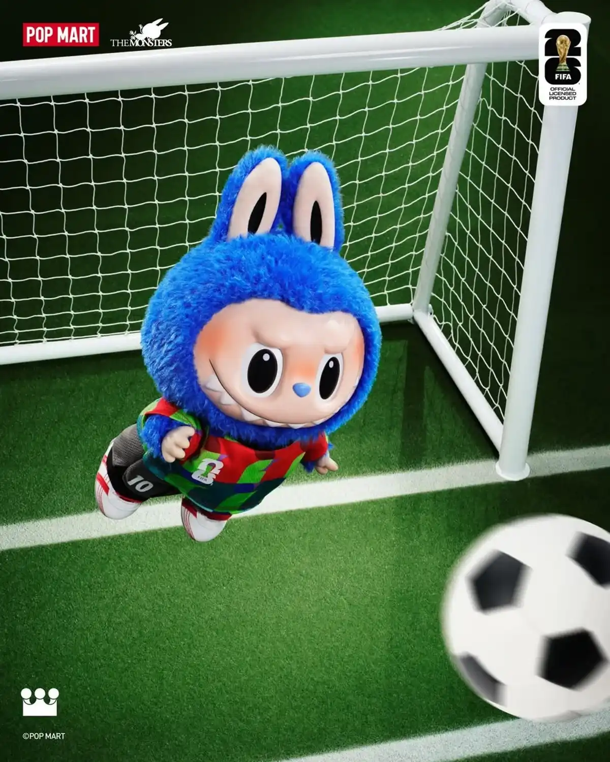 O monstro de pelúcia azul Labubu, vestido com um uniforme de futebol colorido número 10, é capturado no meio do ar, flutuando em frente a uma rede de gol de futebol em um campo verde. Uma bola de futebol em movimento e desfocada está no canto inferior direito. O canto superior esquerdo mostra os logotipos "POP MART" e "THE MONSTERS", e o canto superior direito tem o logotipo oficial de produto licenciado da FIFA.