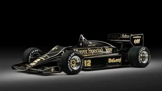 Fotografia colorida de estúdio do carro de corrida John Player Special Lotus-Renault 97T nº 12, exibido contra um fundo preto profundo com iluminação dramática.