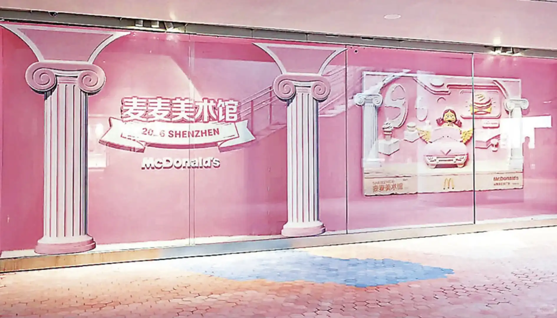 Fachada de vidro de uma unidade temática do McDonald's em Shenzhen, na cor rosa, decorada com colunas gregas ilustradas e textos em chinês.