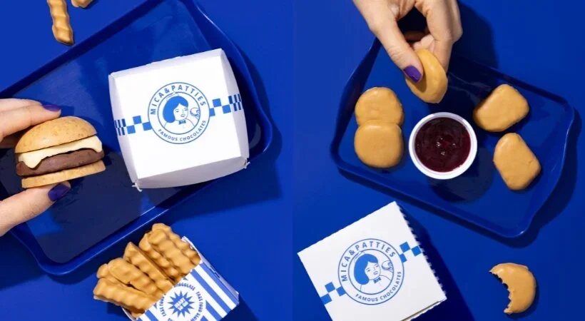 Duas visualizações de chocolates que imitam fast-food. À esquerda, uma mão com unhas roxas segura um pequeno hambúrguer de chocolate e biscoito. À direita, uma mão mergulha um "nugget" de chocolate em um potinho de geléia vermelha, cercado por mais nuggets e caixas de marca "Mica & Patties" sobre um fundo azul royal.