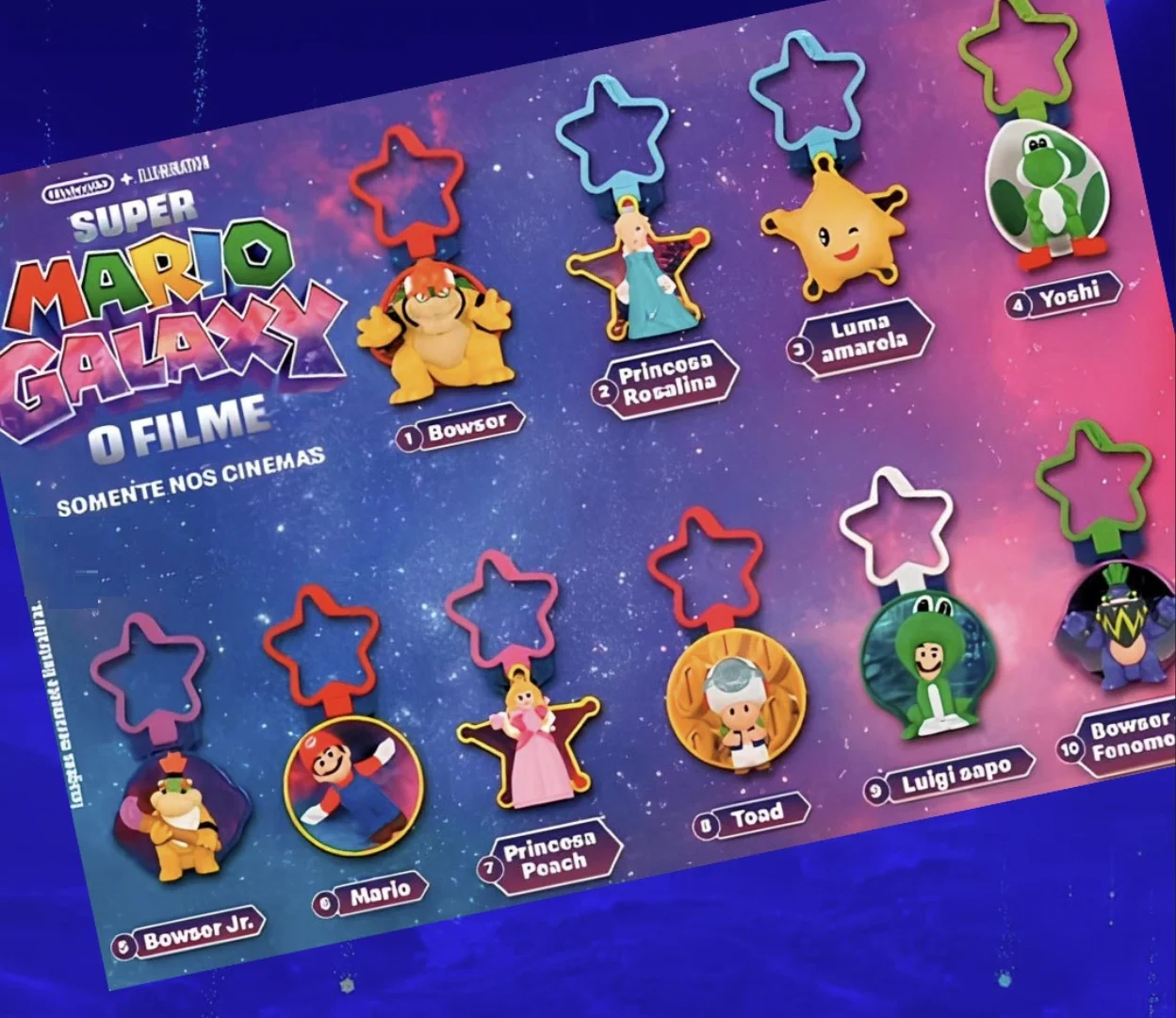 Cartaz promocional apresentando 10 chaveiros coloridos com personagens de Super Mario Galaxy, cada um numerado e com um gancho em formato de estrela.