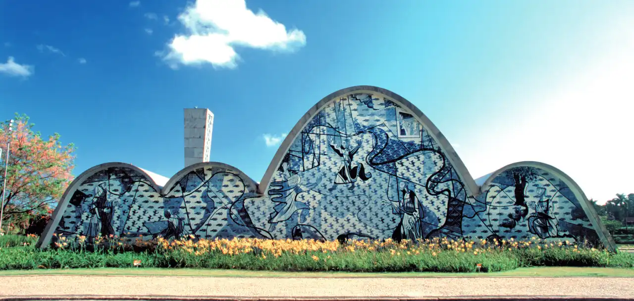 Fachada externa da Igreja de São Francisco de Assis na Pampulha, com seus painéis de azulejos azuis e brancos sob um céu limpo.