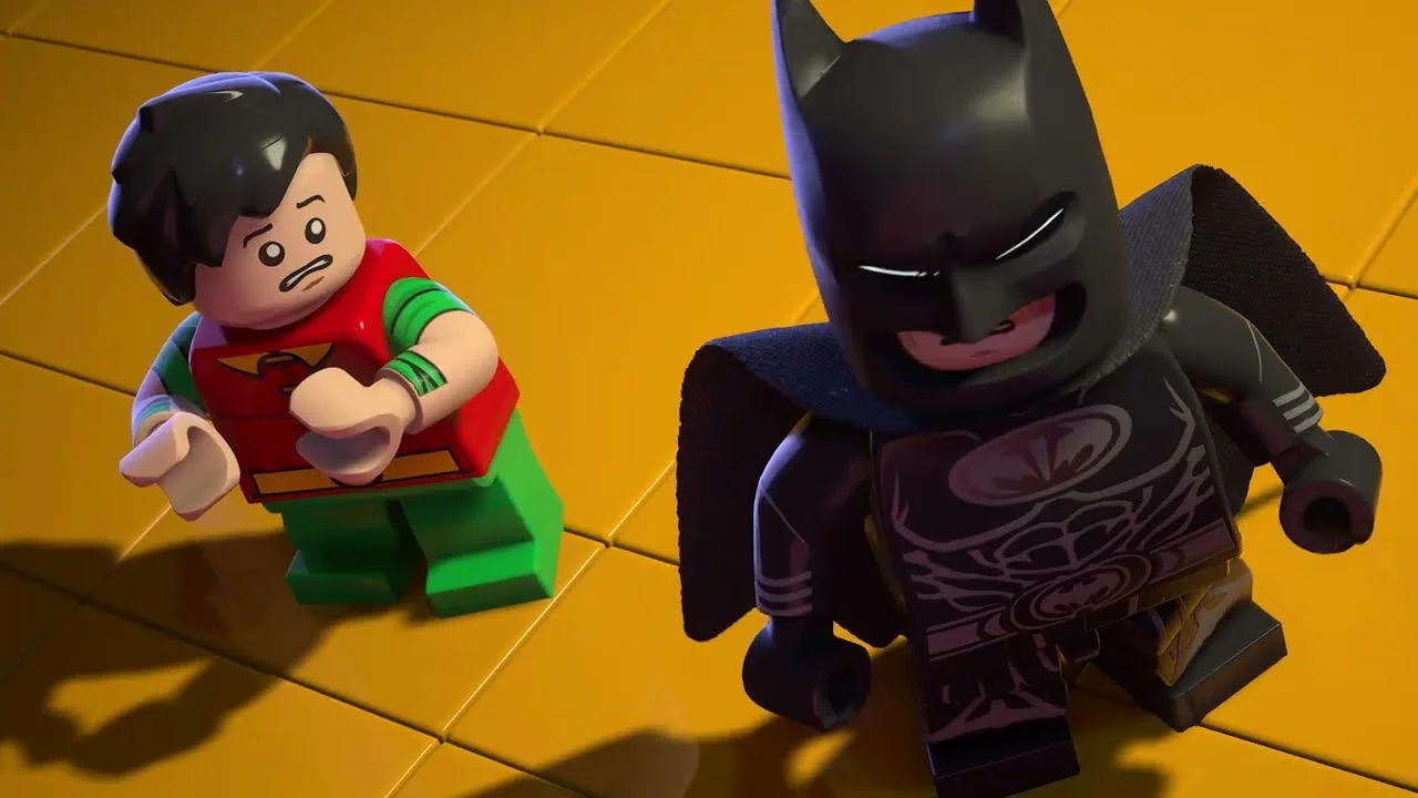 As minifiguras LEGO Batman e Robin, lado a lado, sobre uma superfície de blocos amarelos.