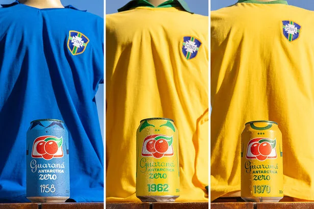 Uma colagem de três painéis mostra a evolução da camisa da seleção brasileira de futebol ao longo de três décadas: 1958, 1962 e 1970. Em cada painel, um manequim veste a camisa correspondente e, na frente dele, há uma lata de Guaraná Antarctica Zero com um design retrô, evocando a estética da época.