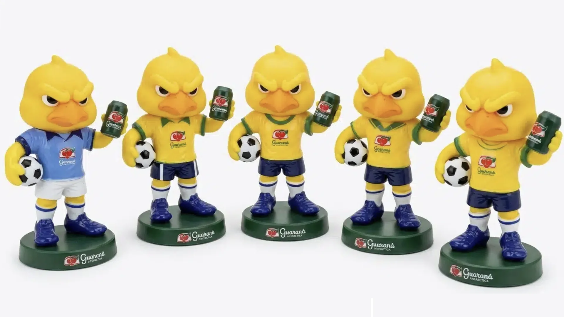Uma foto de frente mostrando uma fileira de cinco bonecos colecionáveis idênticos do Canarinho Pistola, mascote da Seleção Brasileira. Cada boneco veste um uniforme de futebol diferente (um azul, quatro amarelos de anos variados da Copa do Mundo), segura uma bola de futebol sob um braço e uma lata de Guaraná Antarctica no outro. Todos estão em bases circulares verdes com o logo do Guaraná.