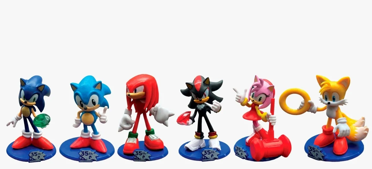Seis figuras de ação de personagens de Sonic the Hedgehog em pé sobre bases circulares azuis com a inscrição "35º ANIVERSÁRIO". Da esquerda para a direita: Sonic (com uma Esmeralda do Caos), Sonic Clássico, Knuckles, Shadow (com uma Esmeralda do Caos), Amy Rose (com seu martelo) e Tails (com um anel de ouro). O fundo é branco puro.