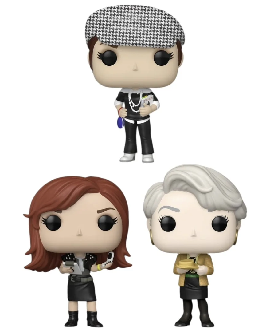 Três bonecos Funko Pop! individuais de O Diabo Veste Prada dispostos em uma formação triangular sobre um fundo branco puro. No topo está Andy Sachs (boina xadrez, segurando o 'Livro da Runway'), e abaixo estão Emily Charlton (cabelo ruivo, segurando o telefone) à esquerda, e Miranda Priestly (cabelo prateado, segurando a xícara de chá amarela) à direita.