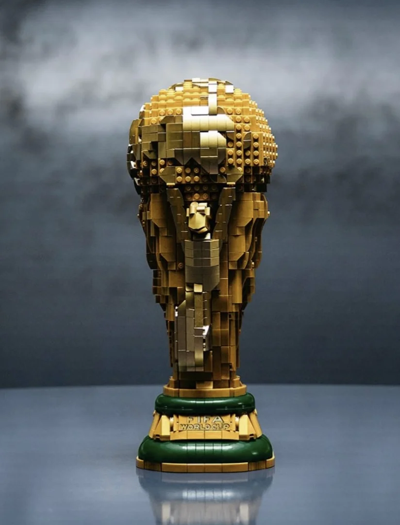 Uma fotografia em close-up de uma réplica do troféu da Copa do Mundo da FIFA construída inteiramente com blocos LEGO.