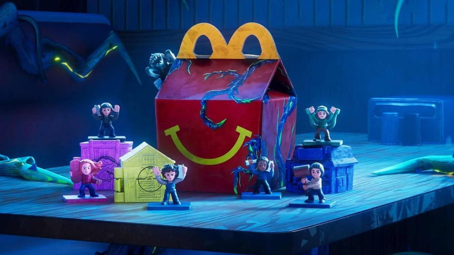 Brinquedos do McLanche Feliz de Stranger Things organizados em uma mesa de madeira.