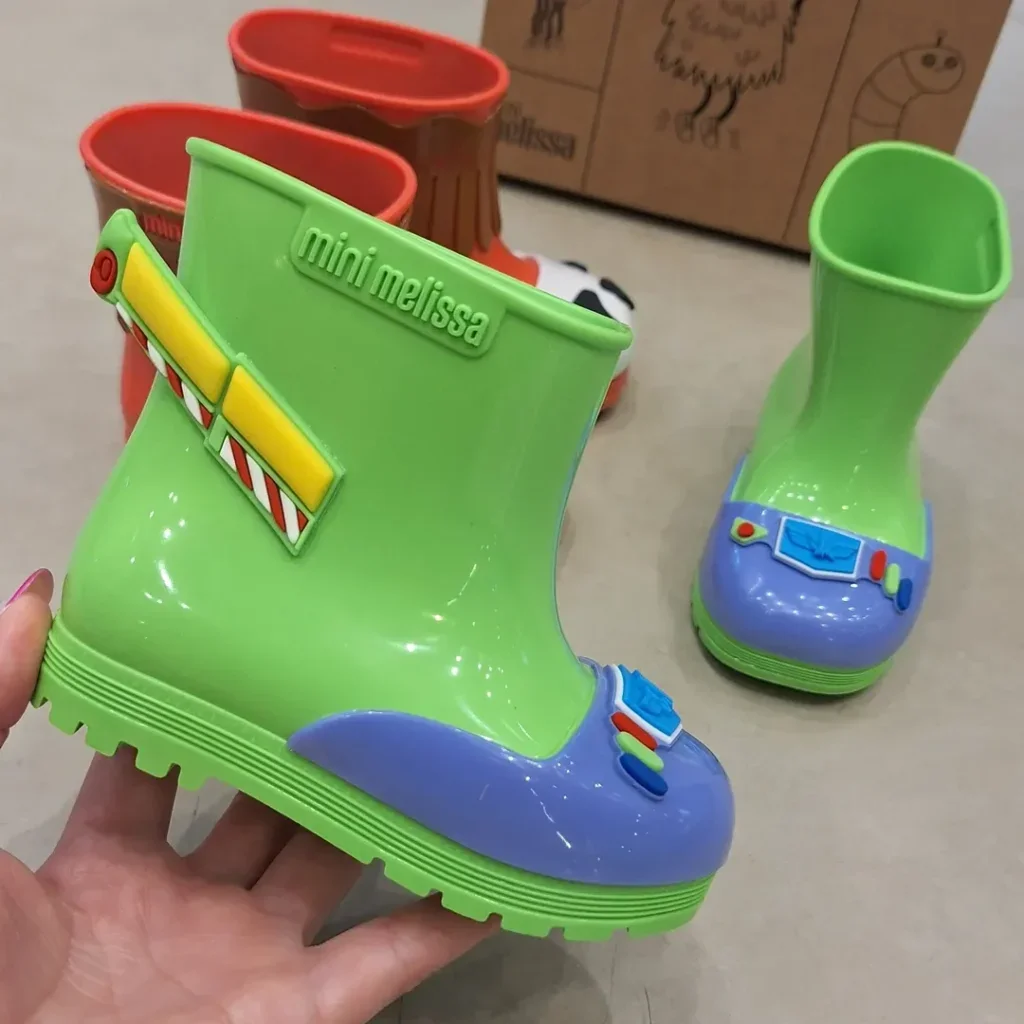 Mão segurando uma bota galocha verde neon com detalhes inspirados no personagem Buzz Lightyear.