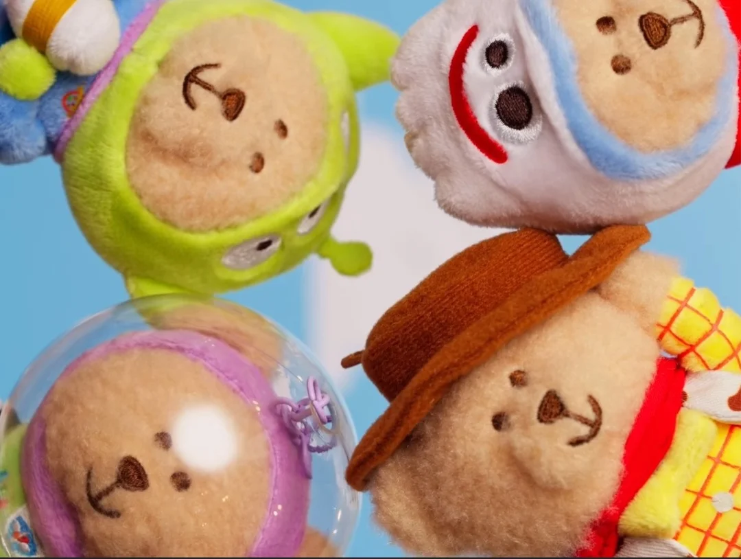 Quatro mini ursinhos de pelúcia fofos com fantasias de personagens de Toy Story (Alien, Forky, Buzz, Woody) vistos de baixo para cima, dispostos em círculo.