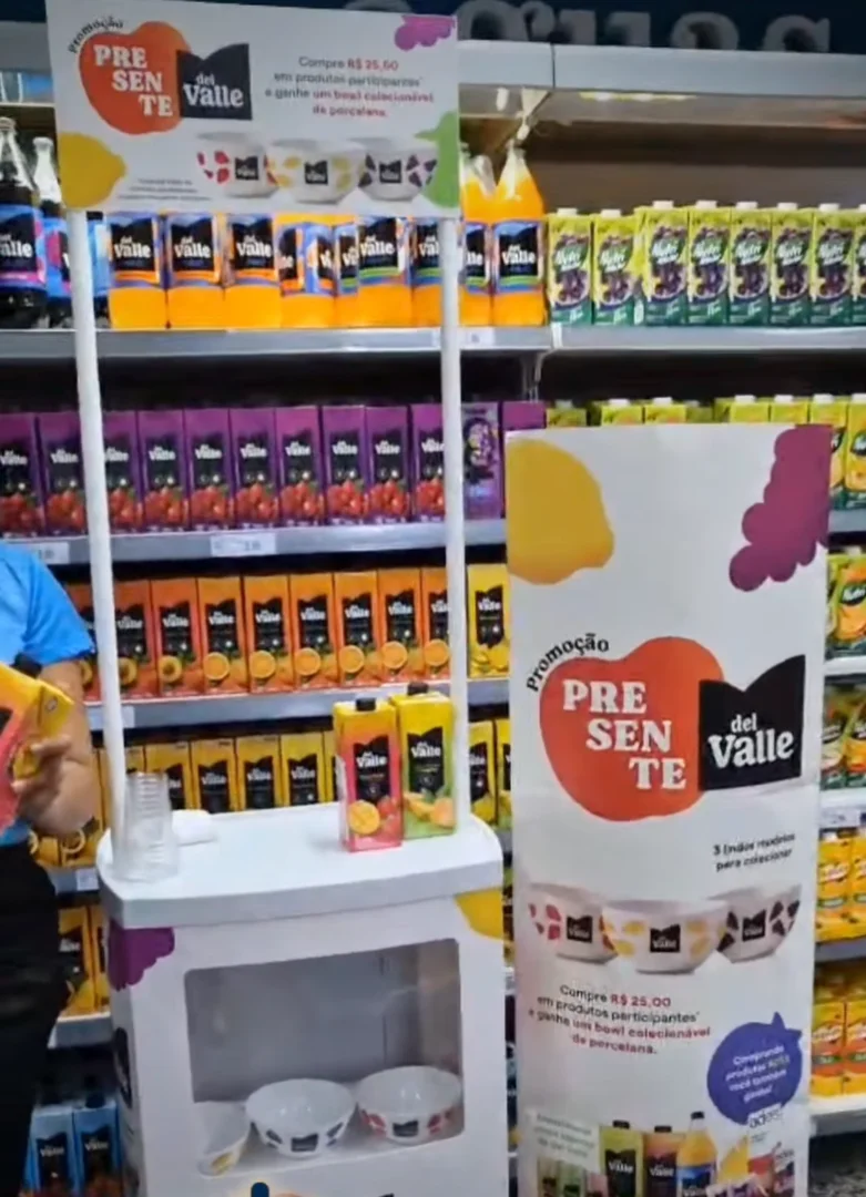 Estande promocional da Del Valle em um corredor de supermercado, exibindo bowls de porcelana colecionáveis como brinde.