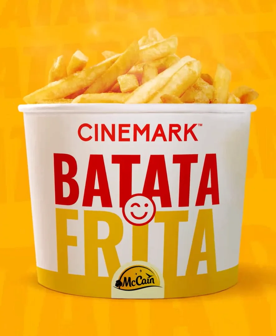 Balde branco cheio de batatas fritas douradas, com os logotipos da Cinemark e da McCain em destaque sobre um fundo amarelo.