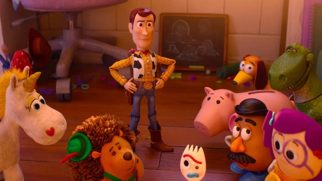 Woody em pé no centro de uma roda formada por vários brinquedos, incluindo Forky, Porquinho e Sr. Cabeça de Batata, em um quarto bagunçado.