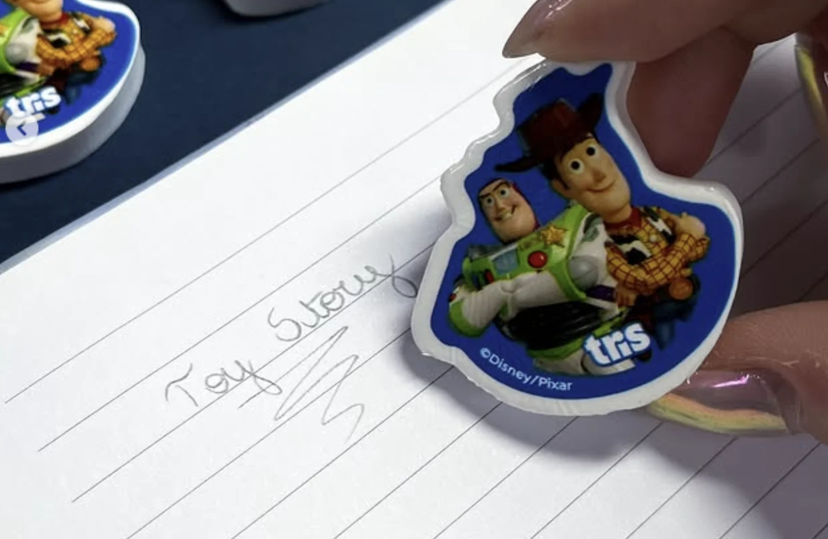 Borracha da coleção Toy Story 5 da Tris com Woody e Buzz sendo usada em caderno escolar.